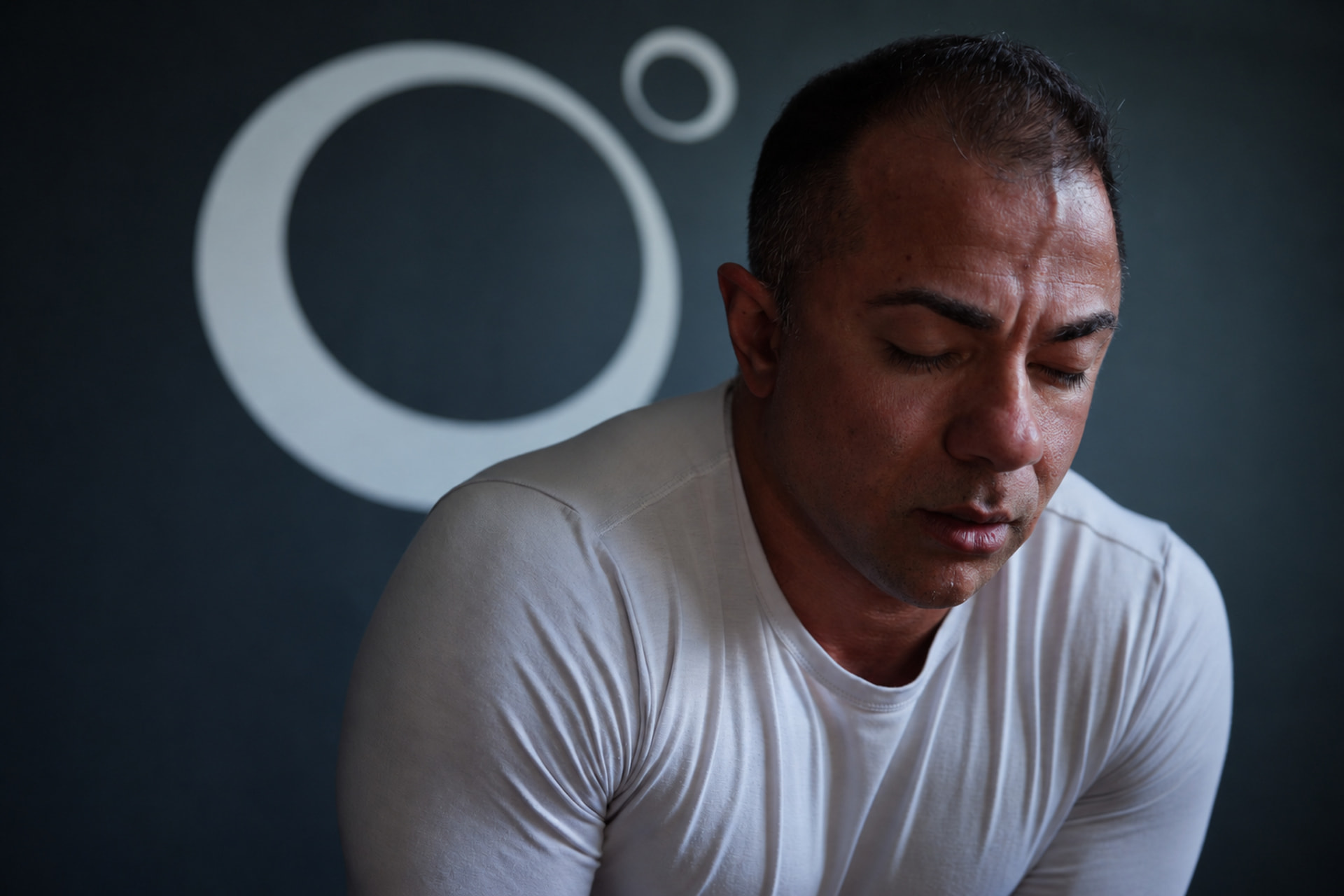 Sam Balooch seated in stillness beneath the ZEN57 mark
